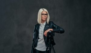 Smart fashionable blogger female in modern clothes and glasses in a studio