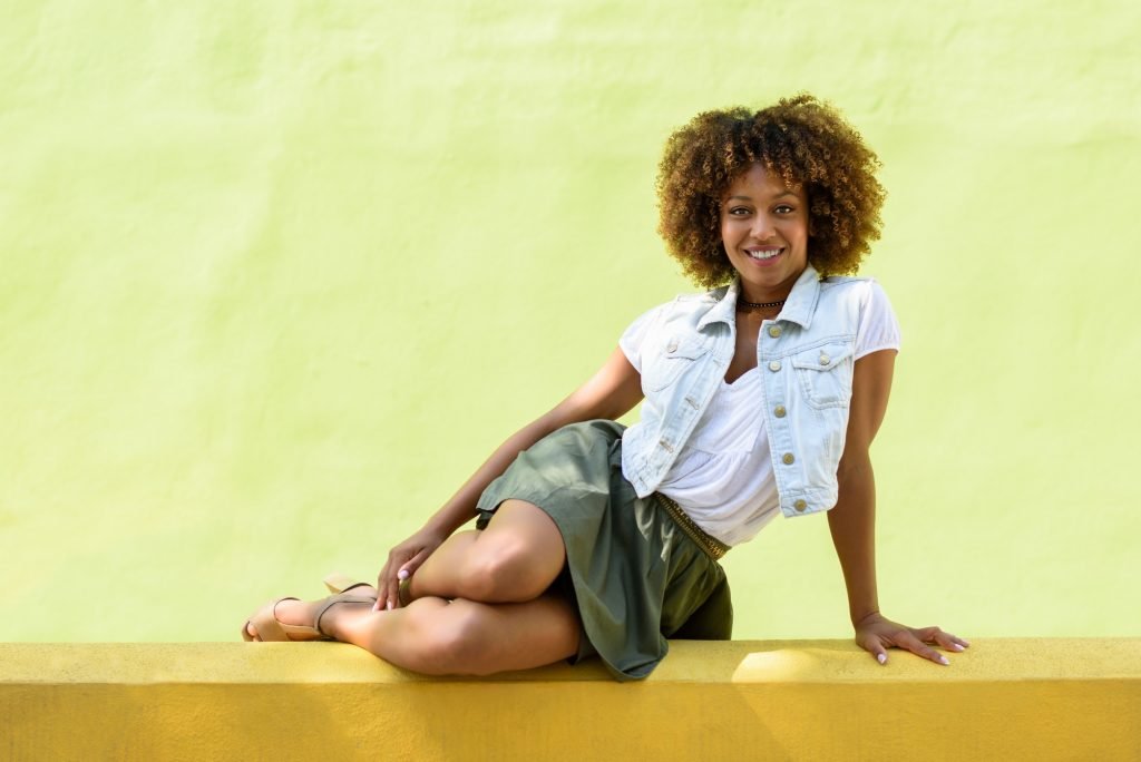Young black woman, afro hairstyle, sitting on an urban wall