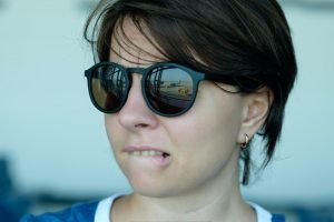 A woman is afraid to fly. She looks at the plane with fear. Focus on sunglasses reflection