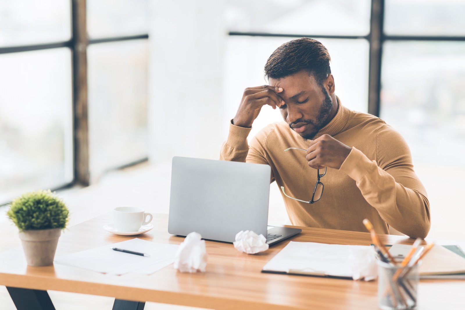 Frustrated black businessman taking off glasses massaging nose