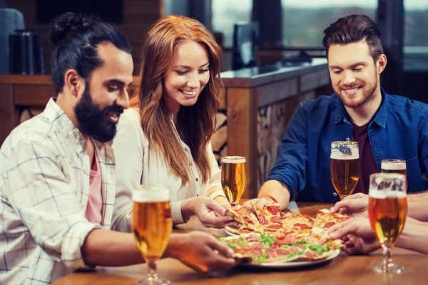 friends eating pizza with beer at restaurant friends eating pizza with beer at restaurant