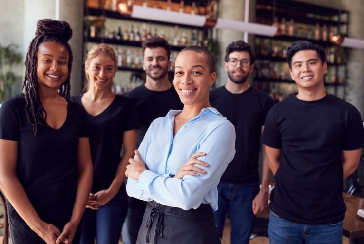 Portrait Of Female Owner Of Restaurant Bar With Team Of Waiting Staff Standing By Counter Portrait Of Female Owner Of Restaurant Bar With Team Of Waiting Staff Standing By Counter