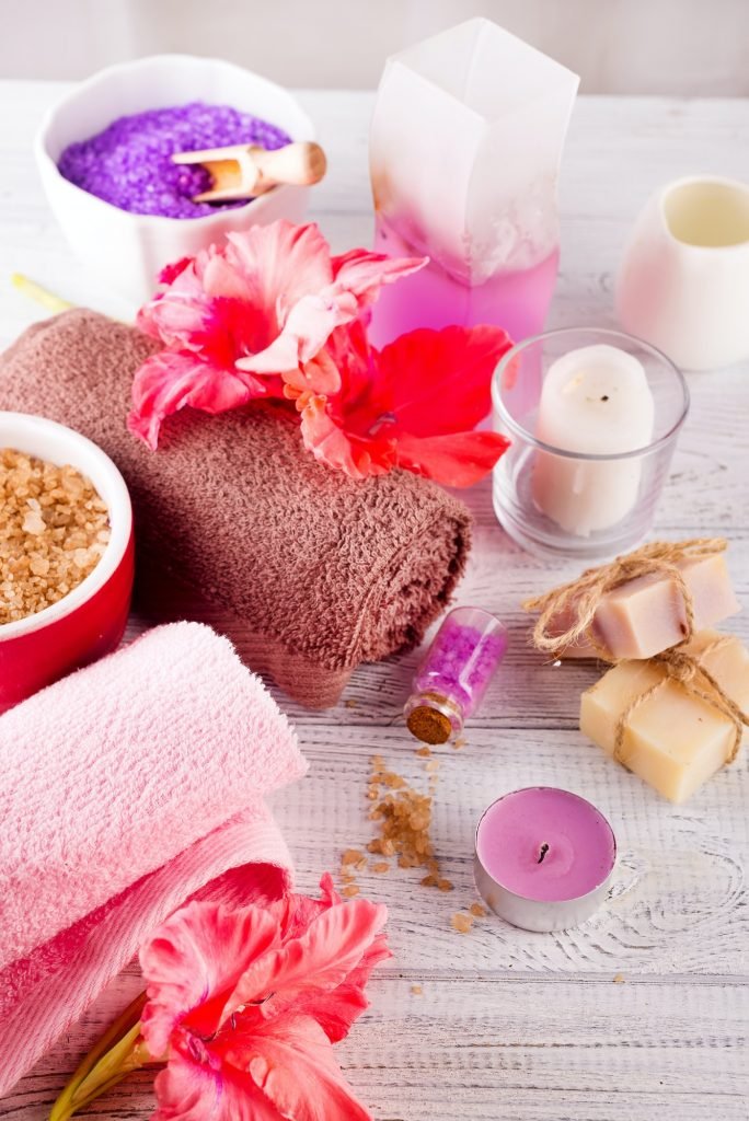 Spa set with flower, candle, bath soap and massage salt on wooden background