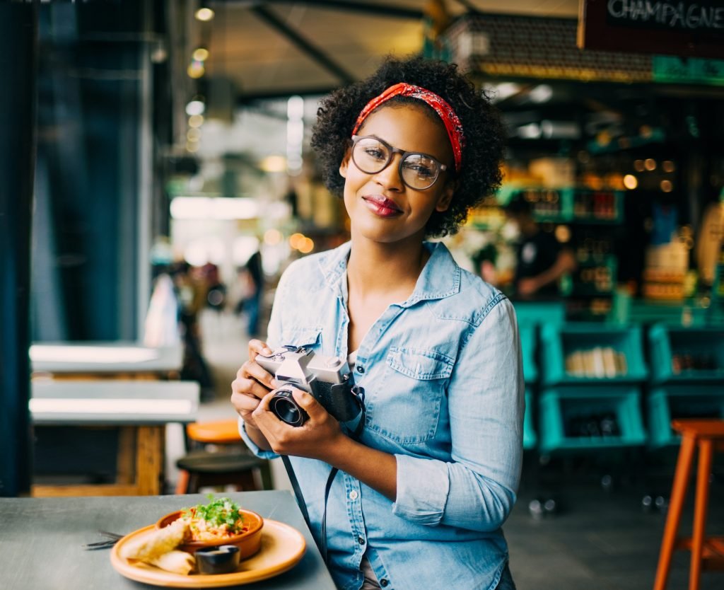 Smiling young woman photographing her food on a cafe counter