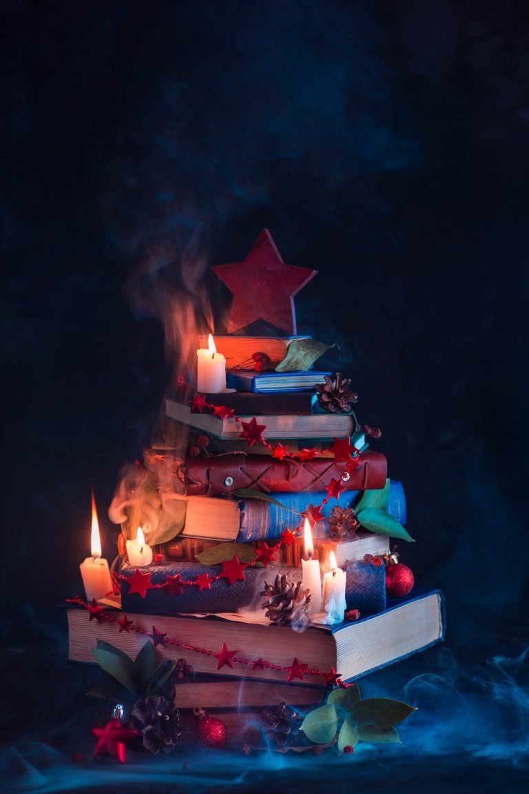 Christmas tree made out of books with candles and mysterious smoke. Winter decorations for readers