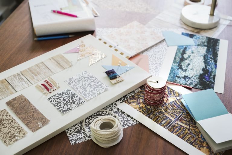 Craft materials, fabric and paper, patterns and a notebook and tablet.