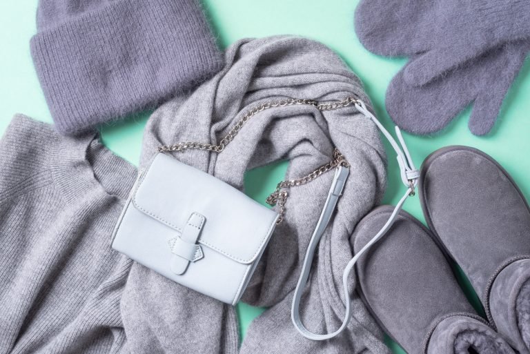 Fashion concept flat lay. Winter warm clothes flat lay on blue background. Wool feminine clothes