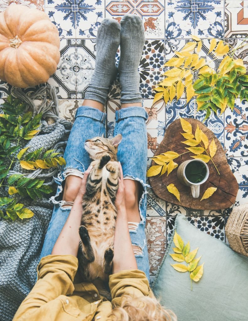 Female sitting on tiled floor with cat in hands
