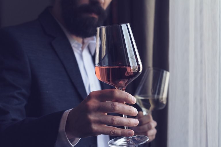 man offering a glass of rose wine