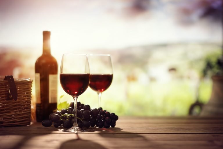 Red wine bottle and glass on table in vineyard Tuscany Italy