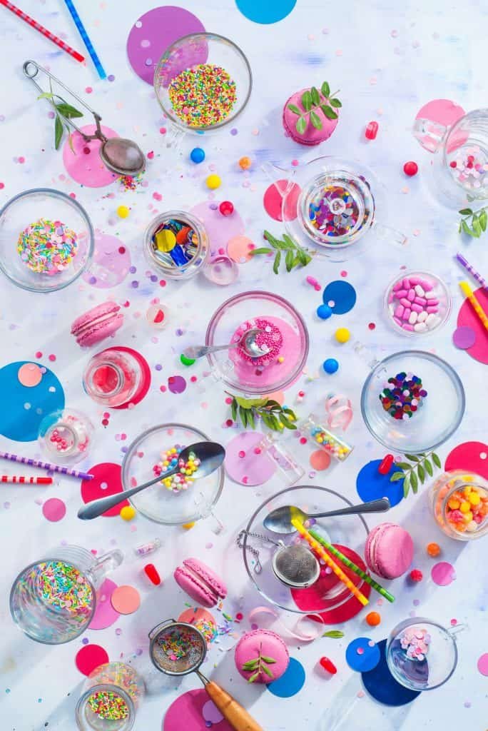 Party supplies in glass tea cups. Sprinkles, confetti, candies, macaroons and birthday candles on a