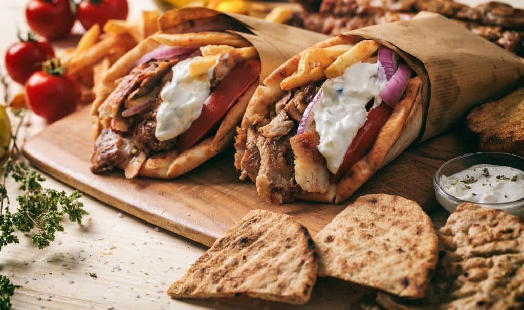 Greek gyros wrapped in pita breads on a wooden table