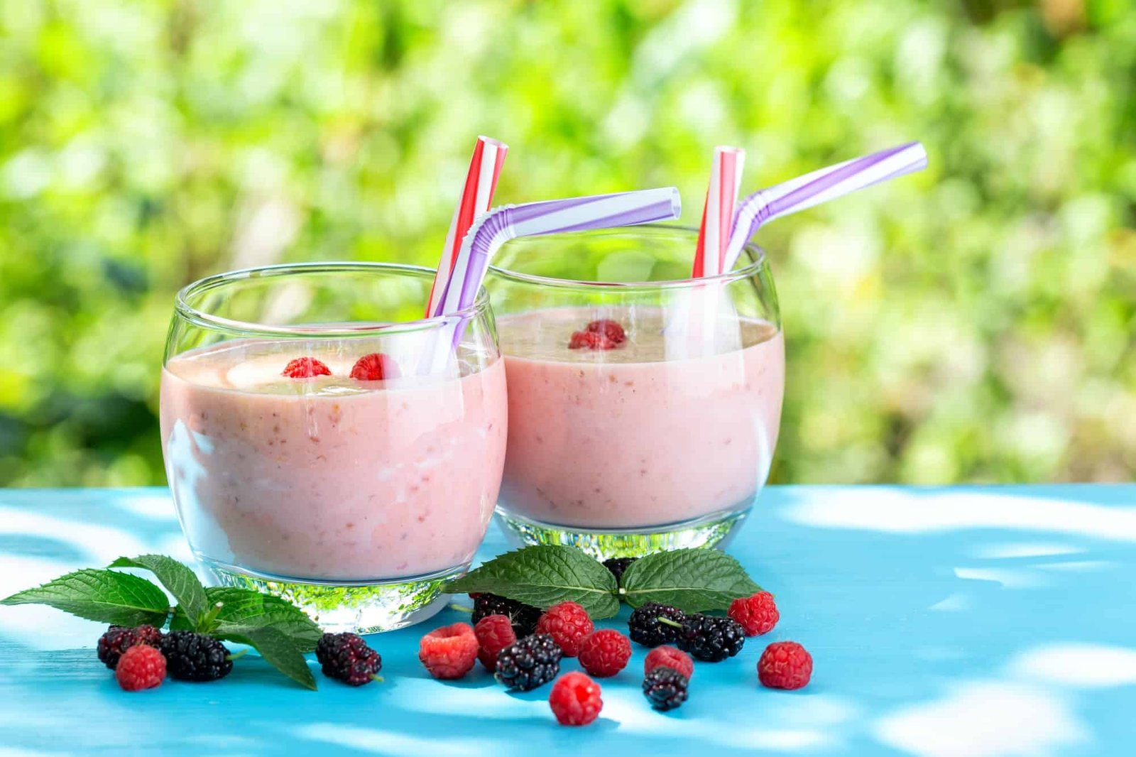Berry smoothie or yogurt in glasses with straws