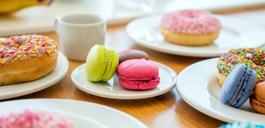 Donuts and macarons on wood, close up view with details