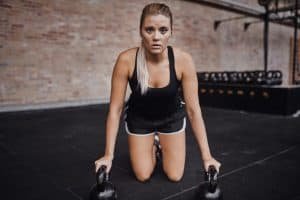Focused young woman working out with weights on a gym floor