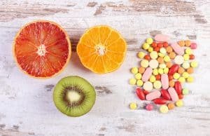 Fresh fruits and colorful medical pills, choice between healthy nutrition and medical supplements