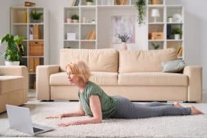 Mature attractive blond woman in activewear exercising in front of laptop