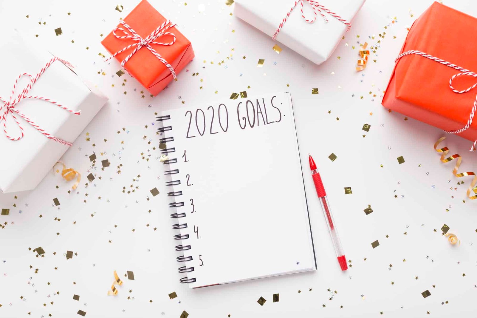 Notepad with goals and Christmas presents on white