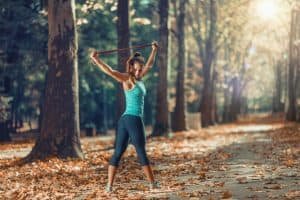 Woman Exercising With Elastic Band Outdoors in The Fall