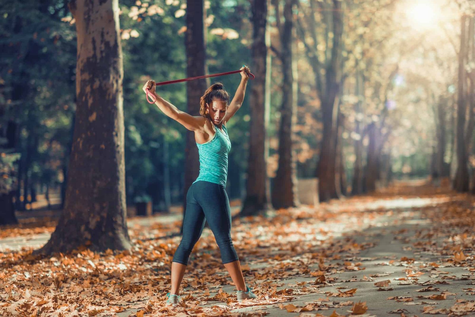 Woman Exercising With Elastic Band Outdoors in The Fall