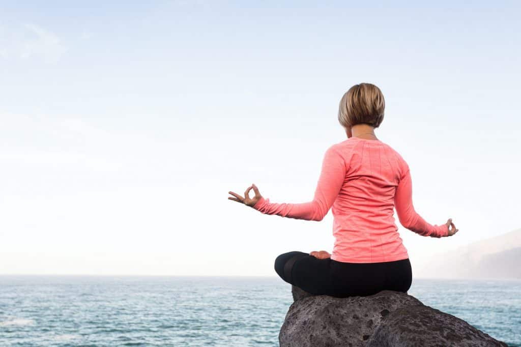 Yoga girl meditating and relaxing in yoga pose, ocean view