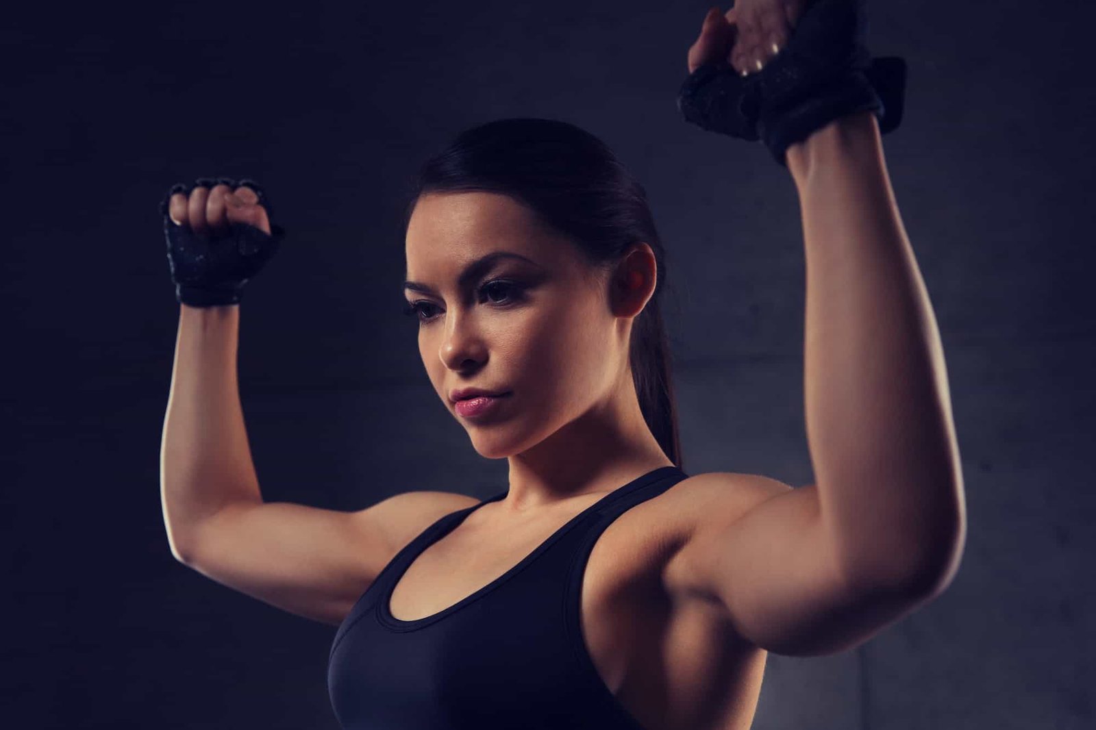 young woman flexing muscles in gym