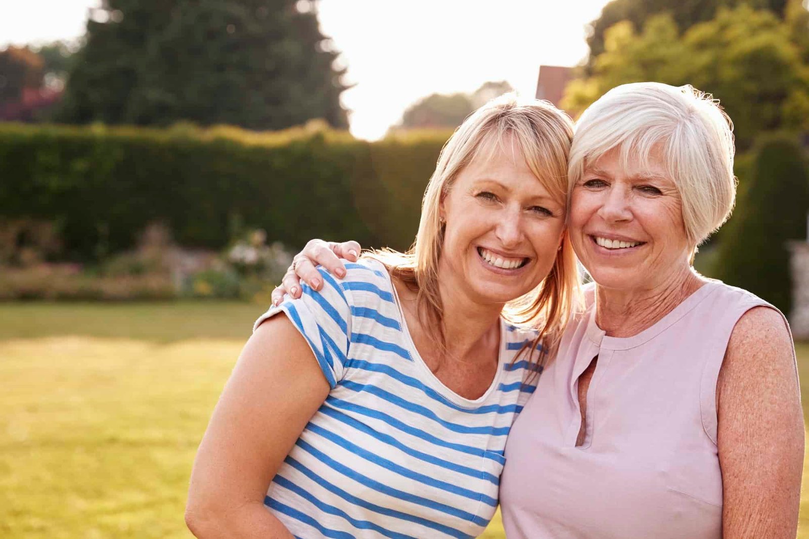 Senior woman and adult daughter embracing in garden