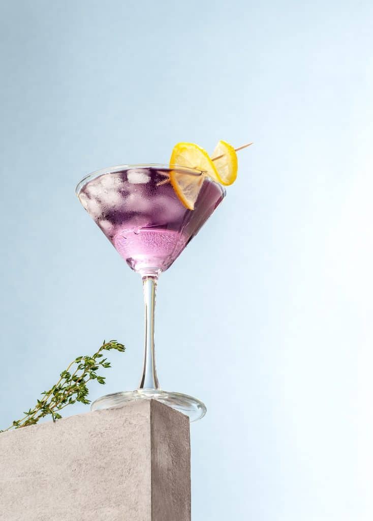 Cold cocktail with lavender syrup and lemon with ice on a light