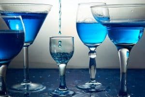 Many glasses with blue champagne or cocktail.