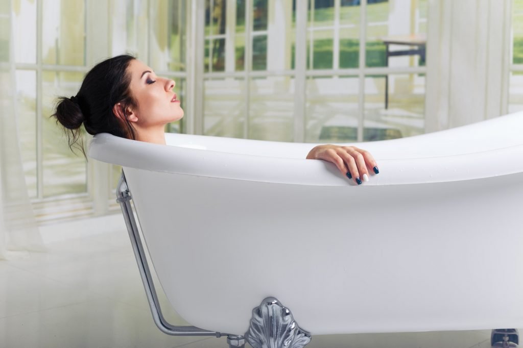 Bathing woman relaxing in bath smiling relaxing with eyes closed