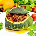 Squash green stuffed with meat and vegetables on dark board