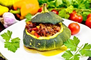 Squash green stuffed with meat and vegetables on dark board