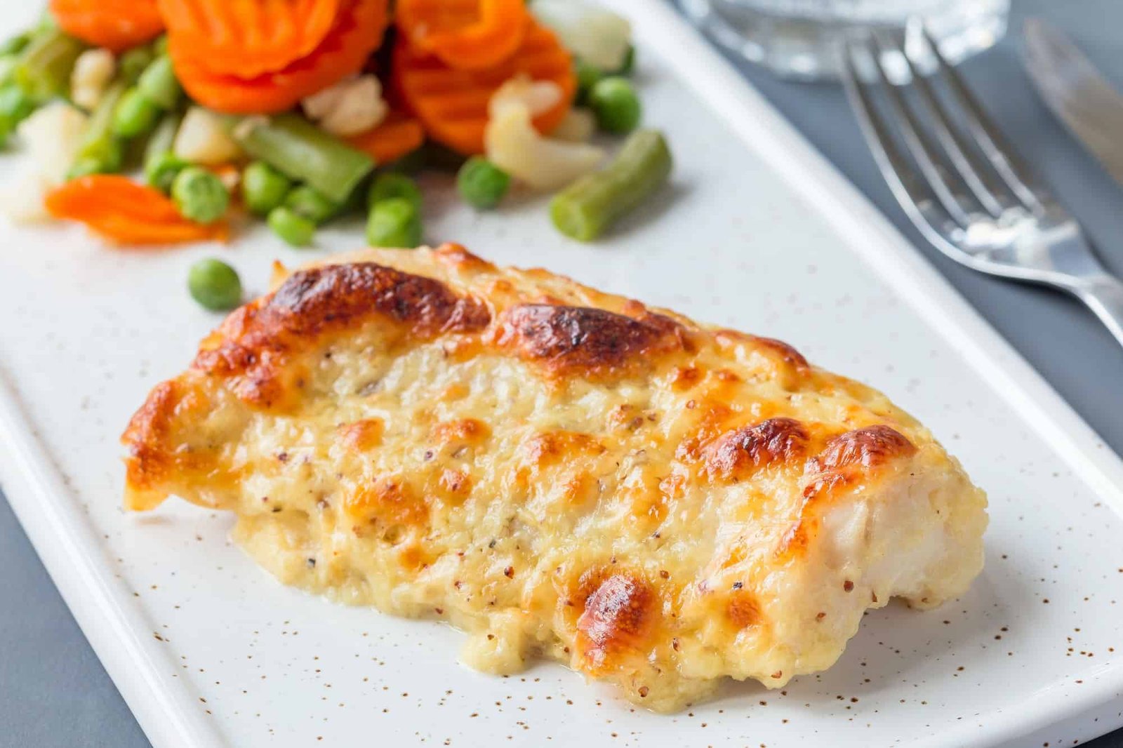 Baked cod fish fillet under cheese, mustard, pepper and cream cr