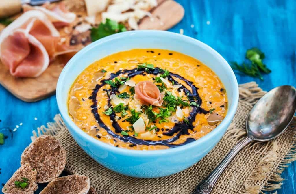 Pumpkin cream soup bowl, served with sesame, prosciutto, parmes