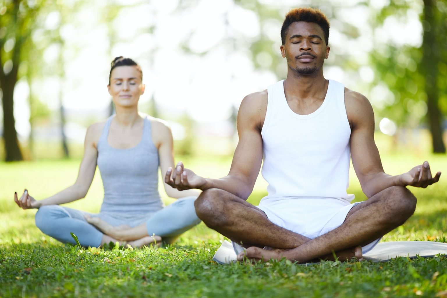 Concentrated yoga students meditating in park