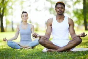 Concentrated yoga students meditating in park