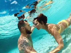 Snorkel couple looking at each other underwater in blue ocean