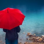 Woman with red umbrella contemplates on rain