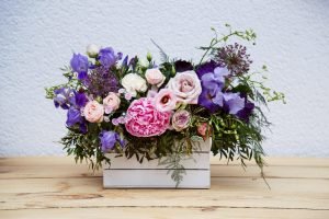 Beautiful tender bouquet of peonies in wooden box on rustic table