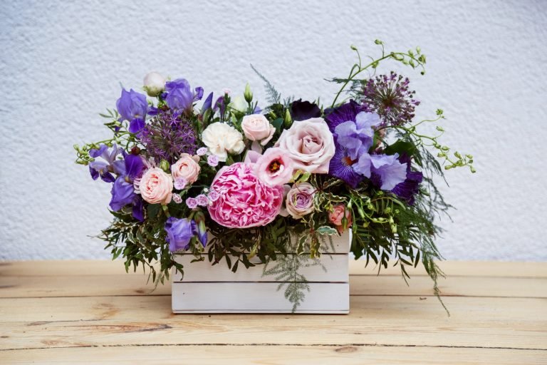 Beautiful tender bouquet of peonies in wooden box on rustic table