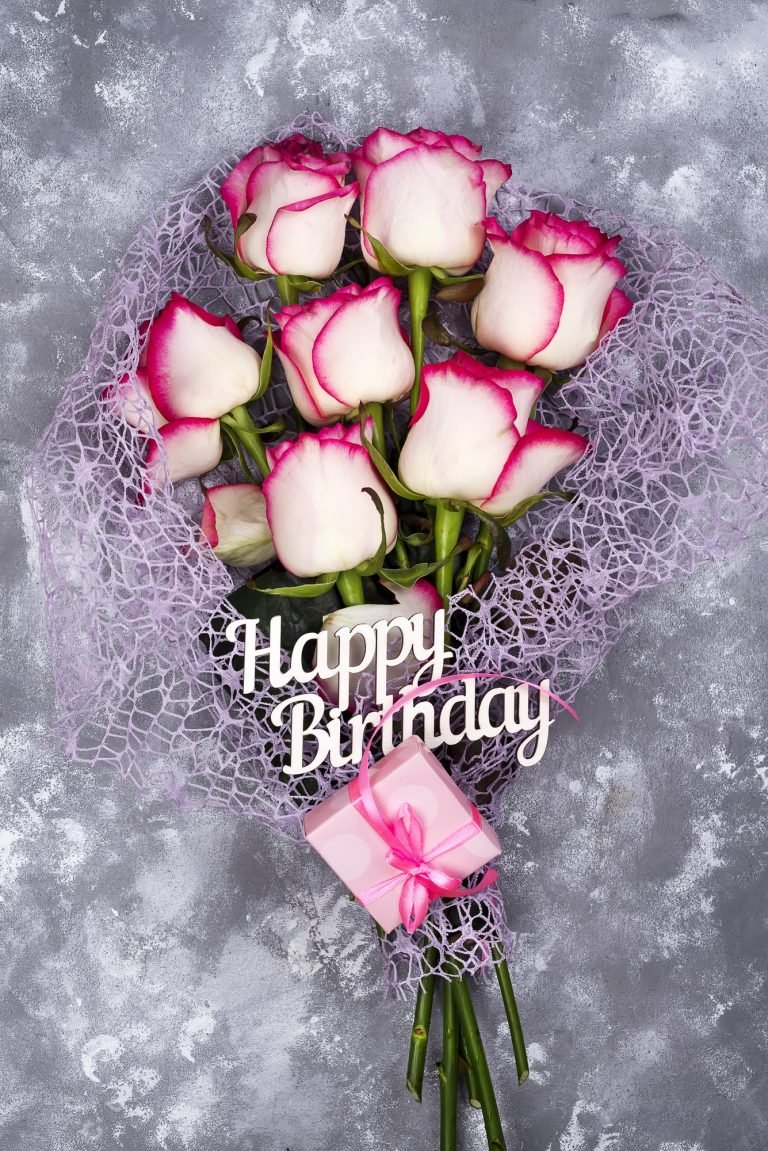 Red white rose flower bouquet with pink gift box on stone table.