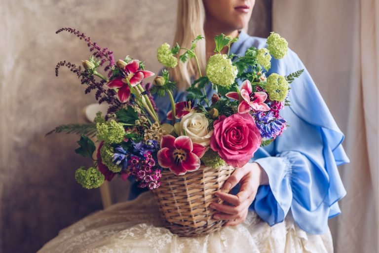 Young woman holding basket with flowers. Vintage, romantic conce