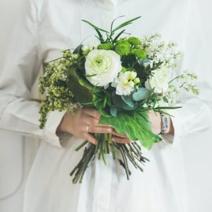 Young woman wearing white clothes holding bouquet. Square crop