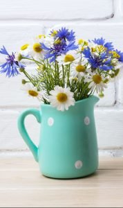 Black coffee mug mockup with cornflower and daisy in pitcher
