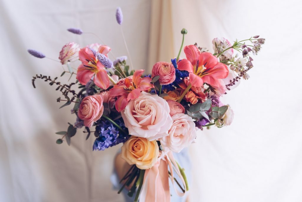 Young woman in a light blue dress holding a bouquet of flowers.