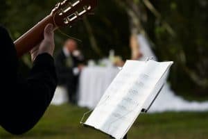Cropped image of a musician and a rack with notes against a pair of newlyweds.