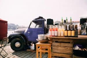 Lemonade, Cider And Other Drinks In Bottles Are Exhibited On A Wooden Counter Near Truck With Food