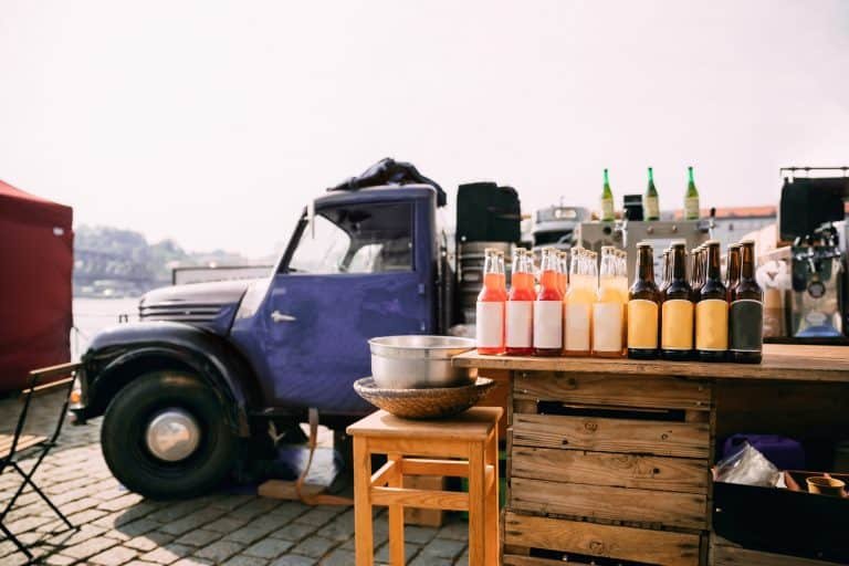 Lemonade, Cider And Other Drinks In Bottles Are Exhibited On A Wooden Counter Near Truck With Food