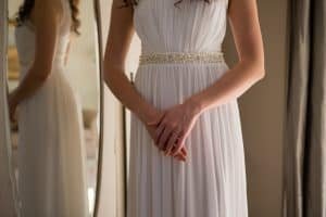 Midsection of bride in dress standing at home