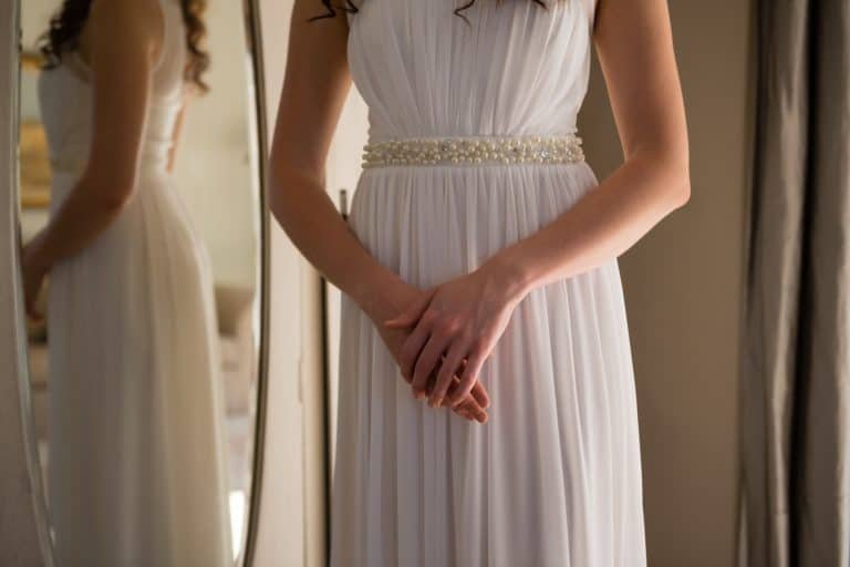 Midsection of bride in dress standing at home
